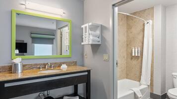 A modern bathroom with a sink, mirror, and shower area.