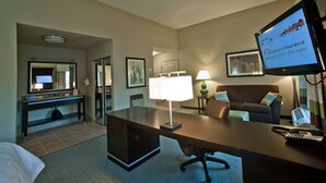 A hotel room with a desk, a chair, a bed, a television, and a lamp. - Hampton Inn & Suites Denison (Denison)