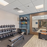 Un gimnasio con equipamiento de ejercicio, incluyendo mancuernas, kettlebells y pelotas de ejercicios.