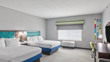 Habitación de hotel con dos camas, un escritorio, una silla, un televisor y una ventana con persianas.