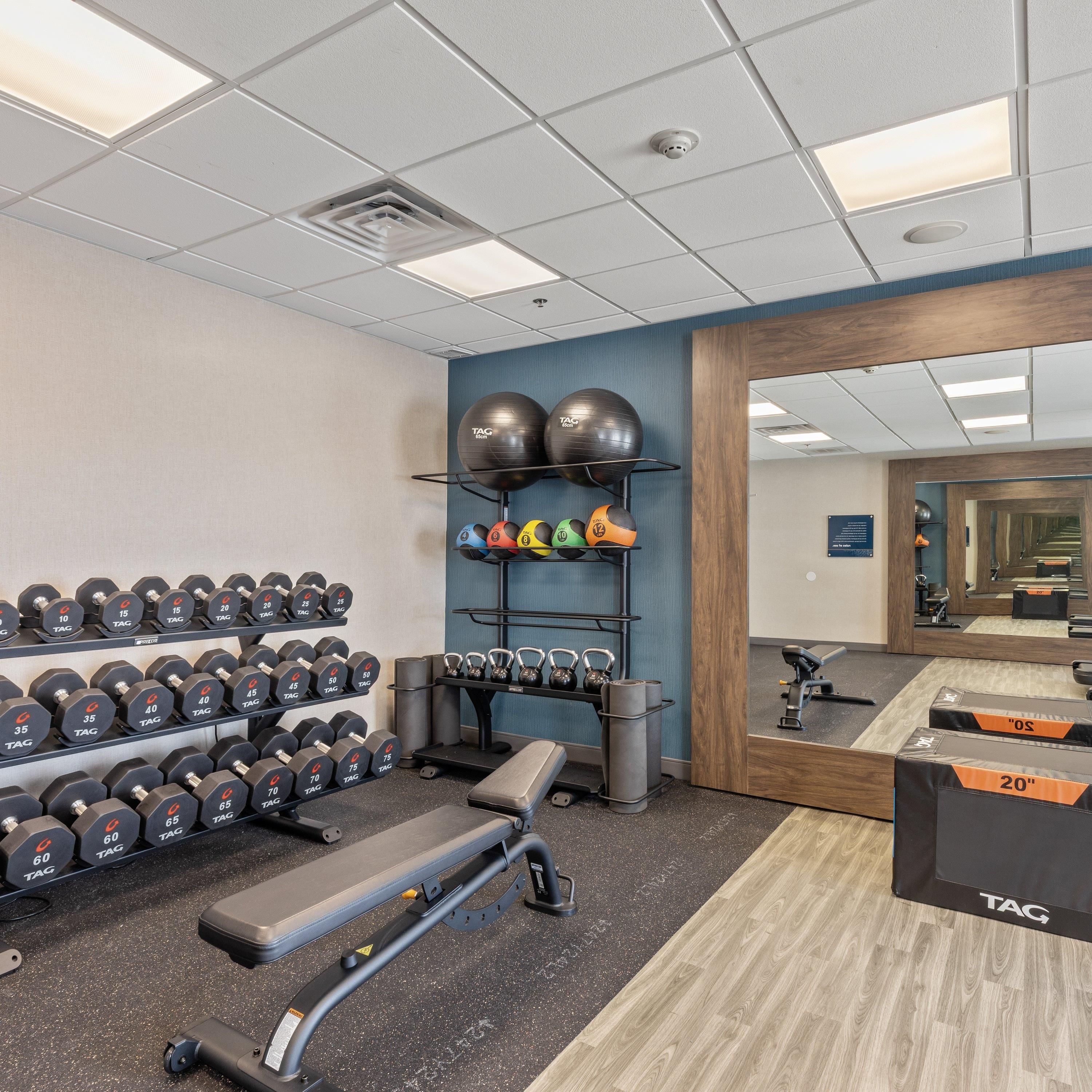 A gym with exercise equipment, including dumbbells, kettlebells, and exercise balls.