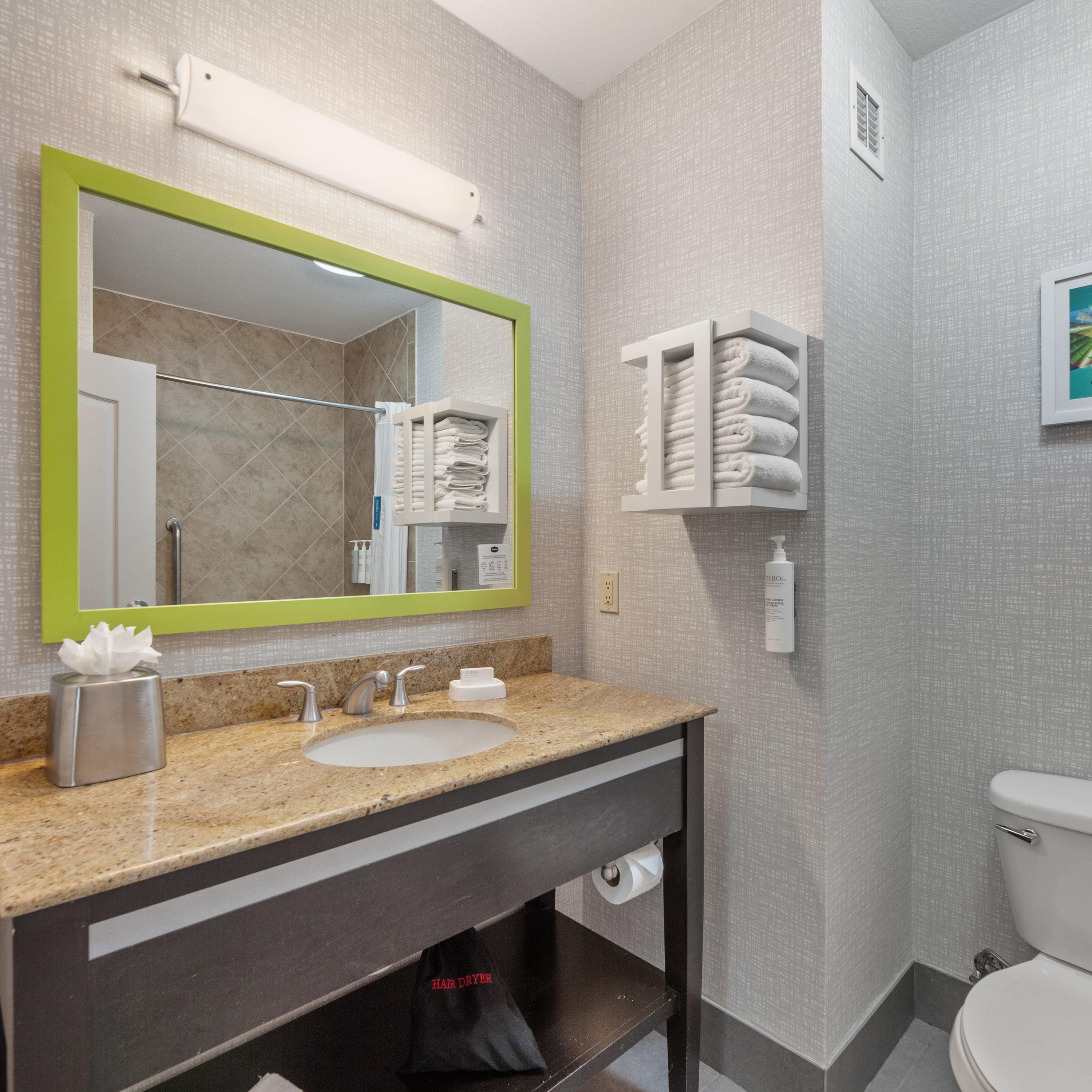 Ein Badezimmer mit Waschbecken, Spiegel, Handtuchhalter und Toilette.