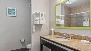 Un baño moderno con encimera de granito, un espejo grande y un secador de pelo.