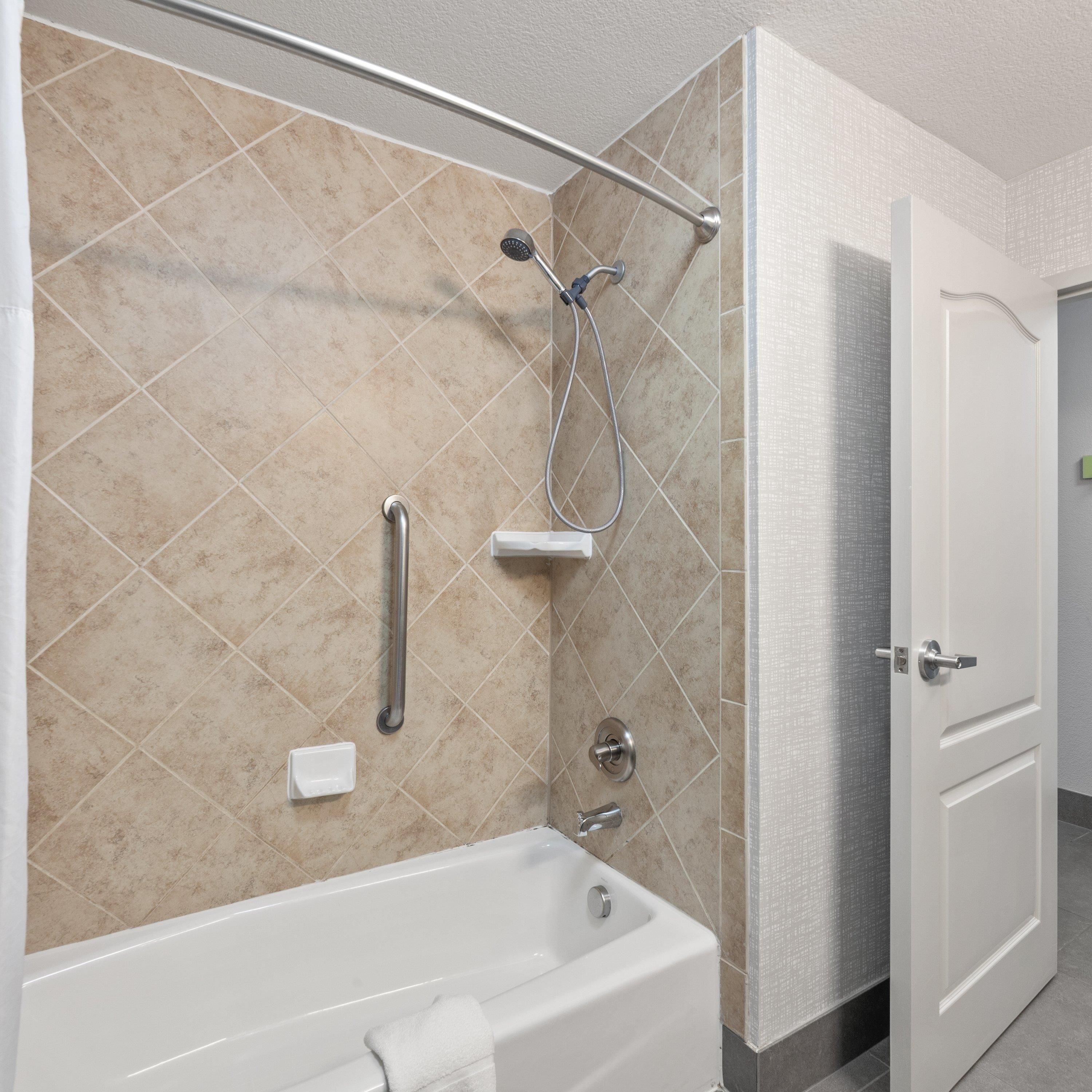 Un baño moderno con bañera, ducha y barras de apoyo.