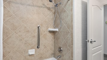Un baño moderno con bañera, ducha y barras de apoyo.