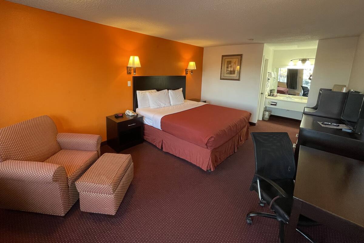 A hotel room with a bed, a desk, a chair, and a television.