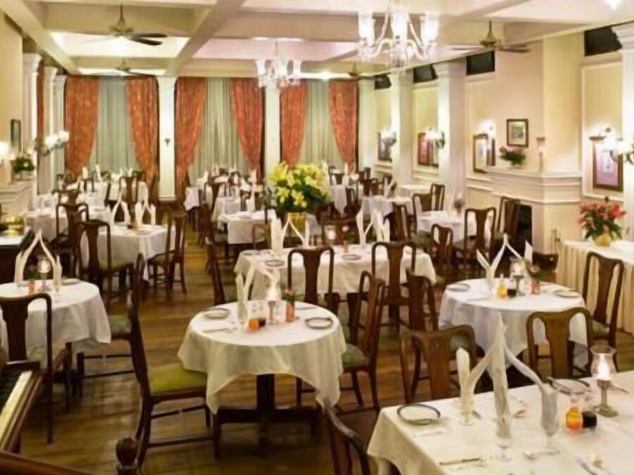 A formal dining room with round tables, chairs, and chandeliers.