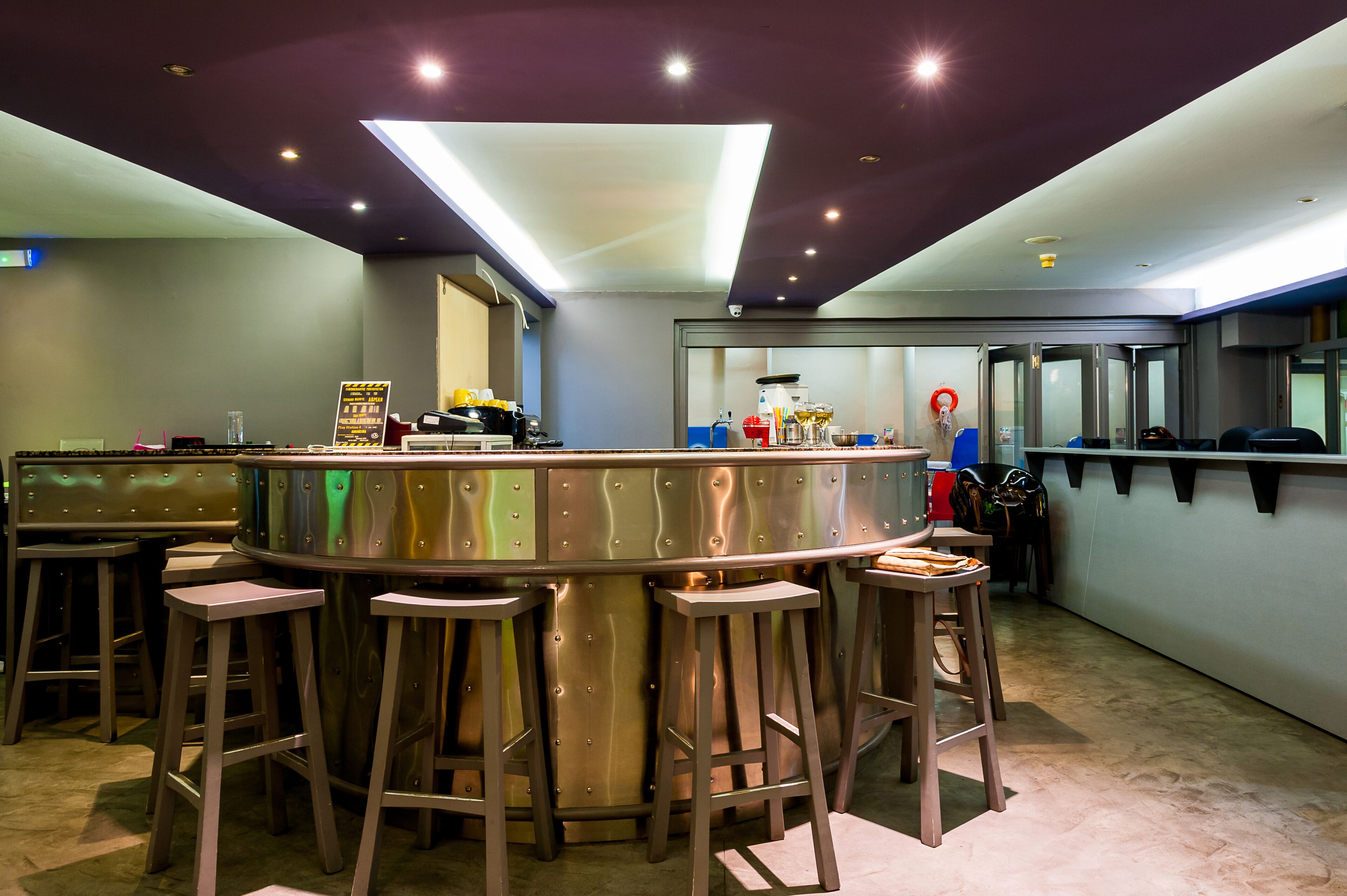 A bar area with stools, a counter, and a kitchen in the background.
