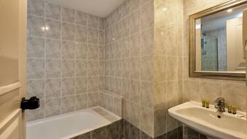 A bathroom with a bathtub, a sink, and a mirror.