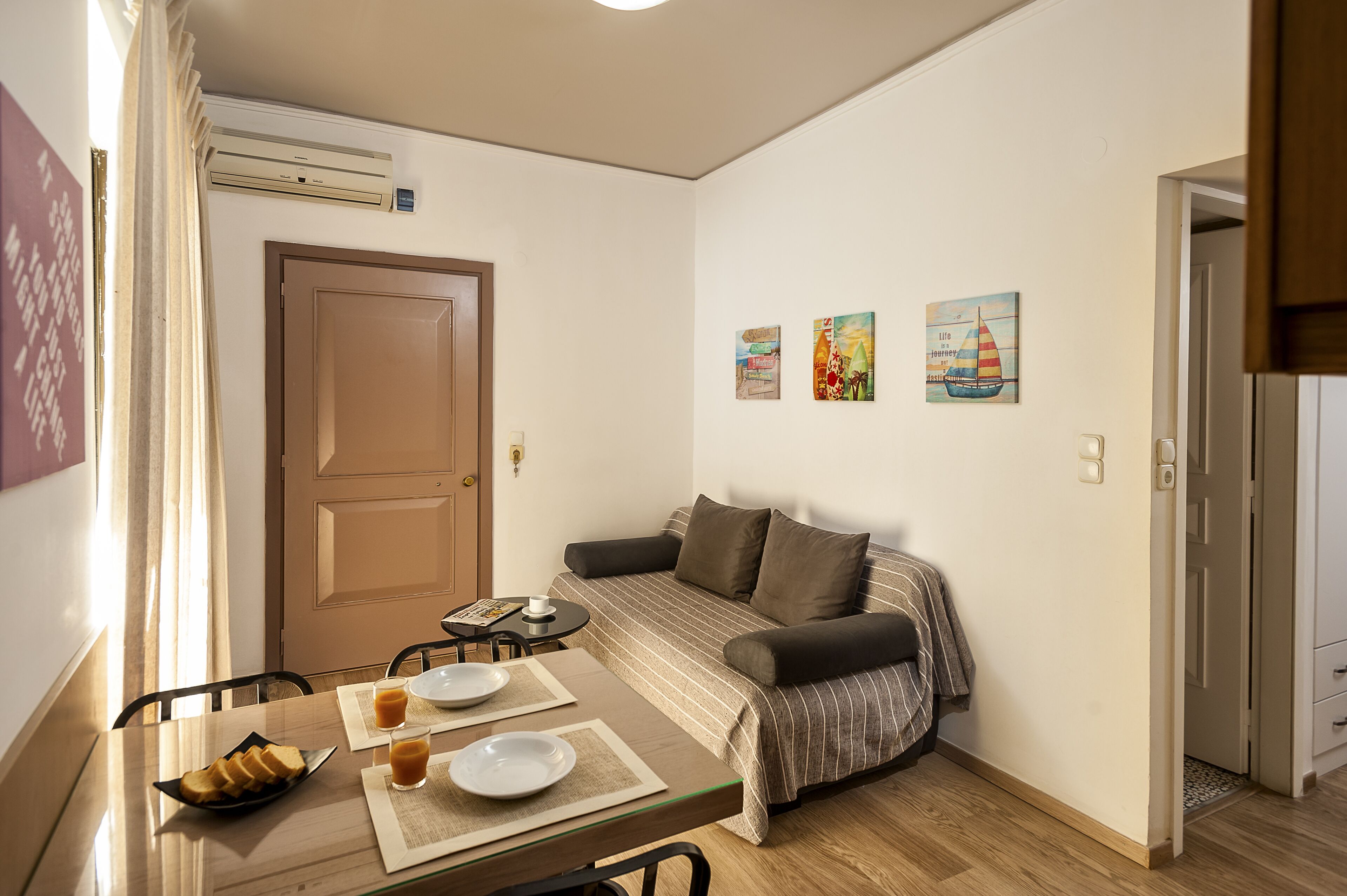 A small, well-lit room with a bed, a table with breakfast items, and a door.