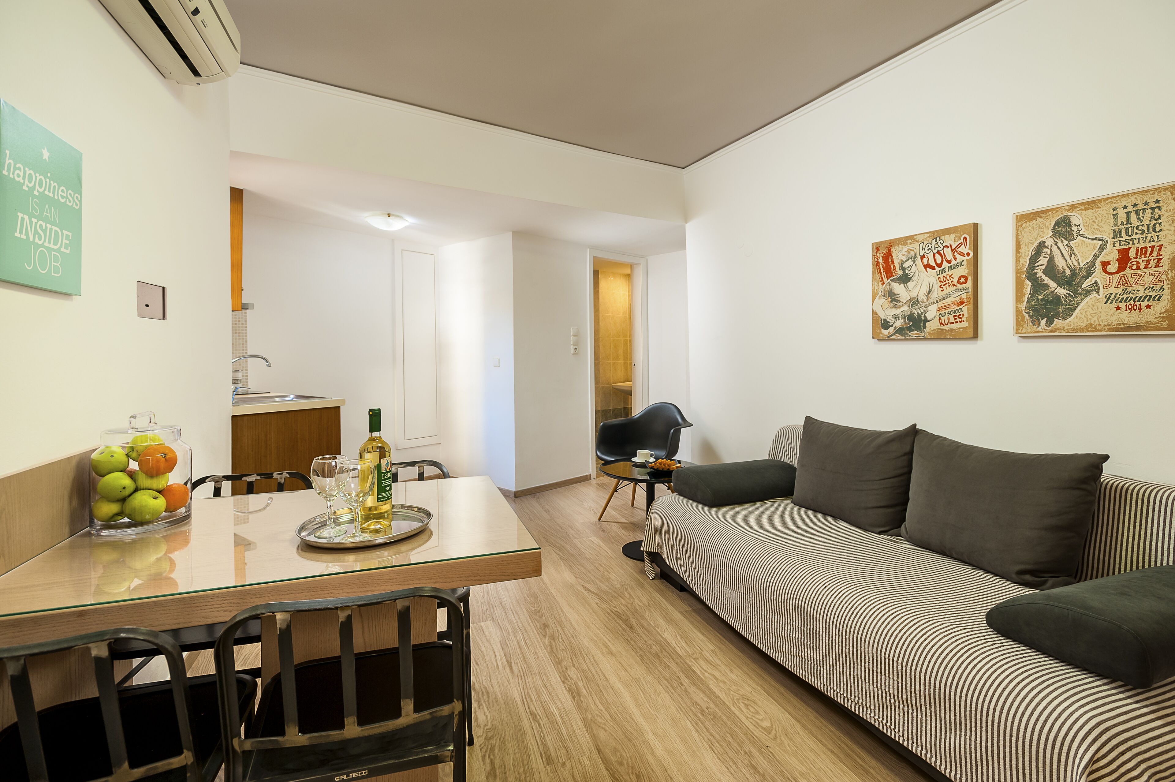 A modern living room with a sofa, a dining table with chairs, and a kitchen area in the background.