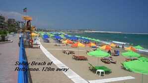 Una playa con hileras de sombrillas y sillas de playa, una torre de salvavidas y una vista despejada del mar.