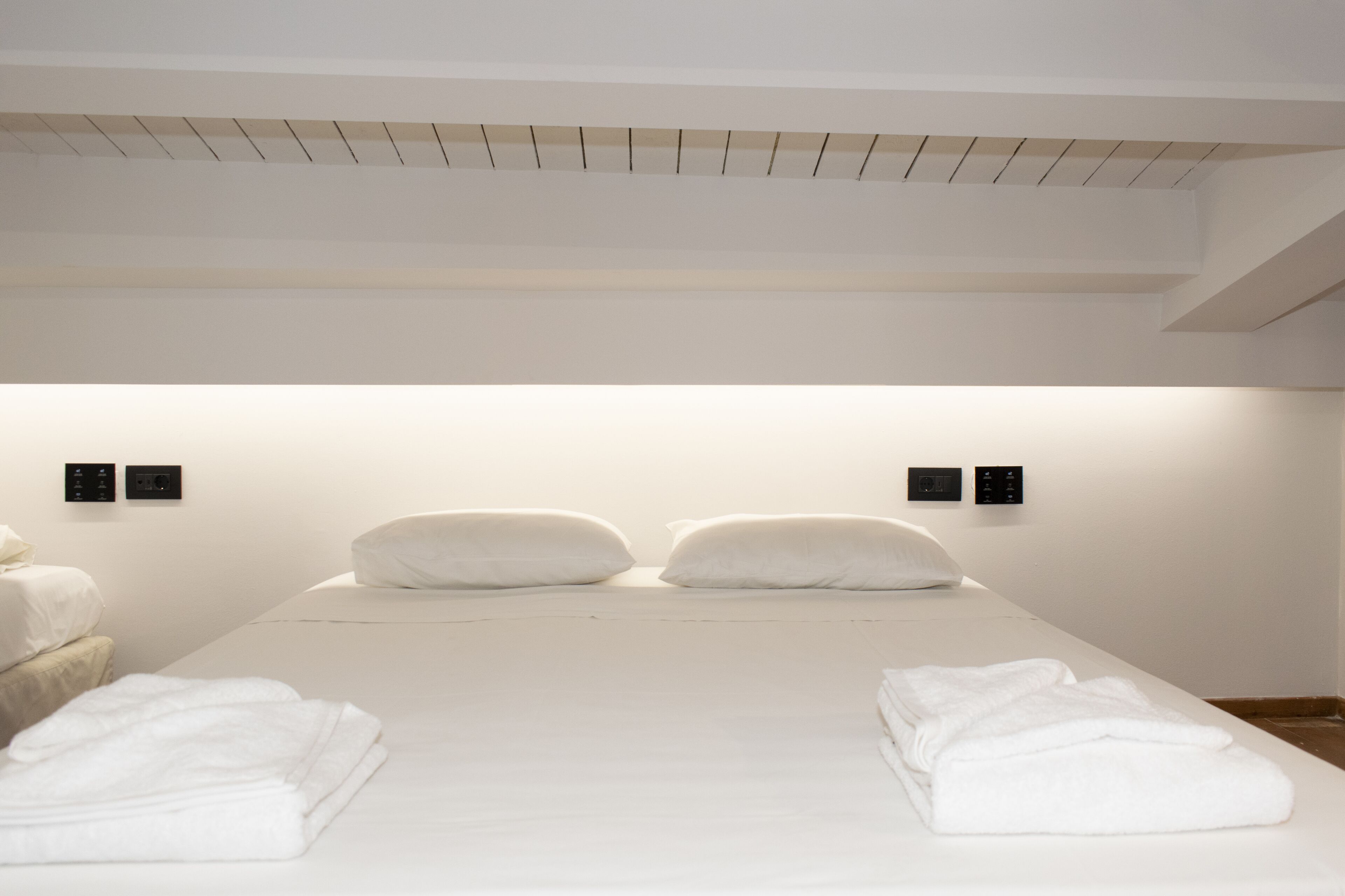 A minimalist hotel room with a large bed, two bedside tables, and a neutral color scheme.