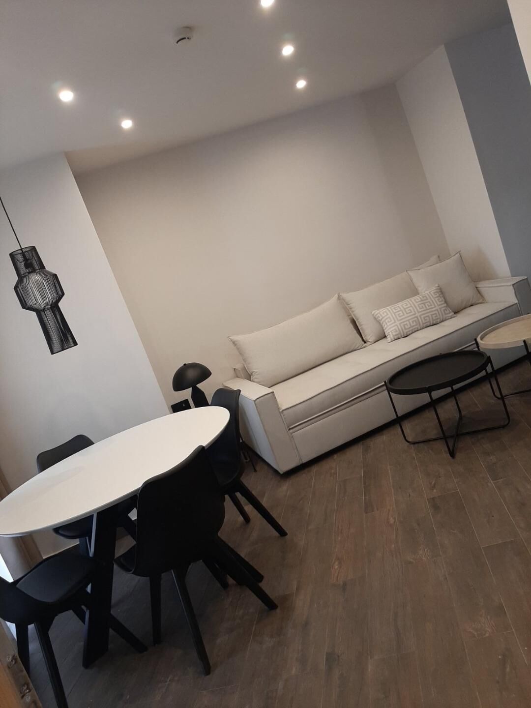 A modern living room with a white sofa, a round dining table, and black chairs.