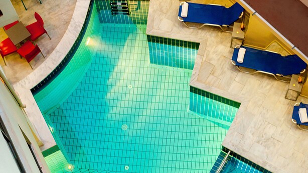 Una piscina con sillas de descanso azules y sillas rojas alrededor.