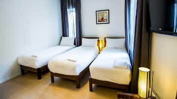 A hotel room with two single beds, a framed picture on the wall, a TV, and a lamp.