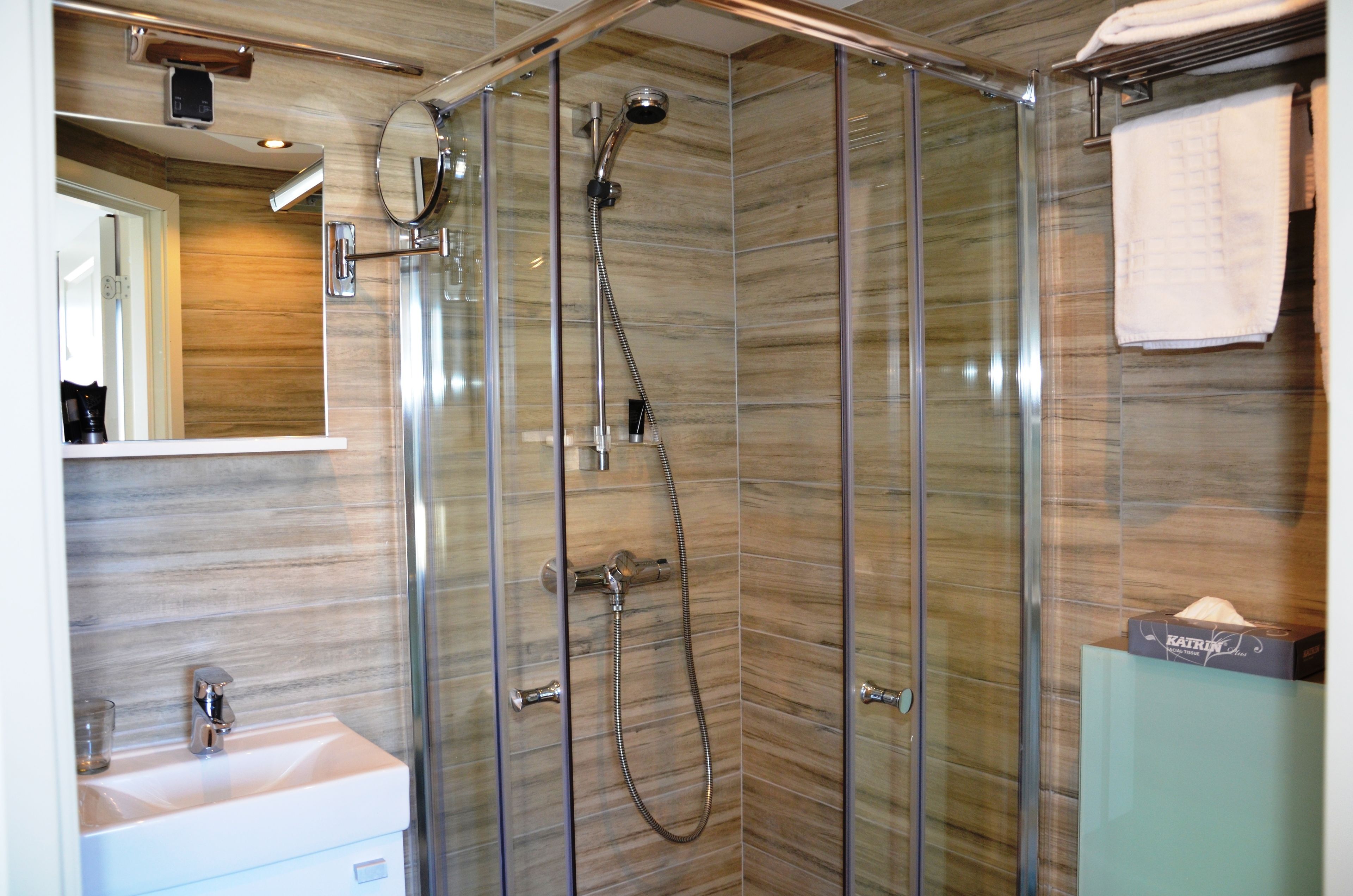 Een moderne badkamer met een douchecabine van glas, een wastafel en een handdoekhouder.