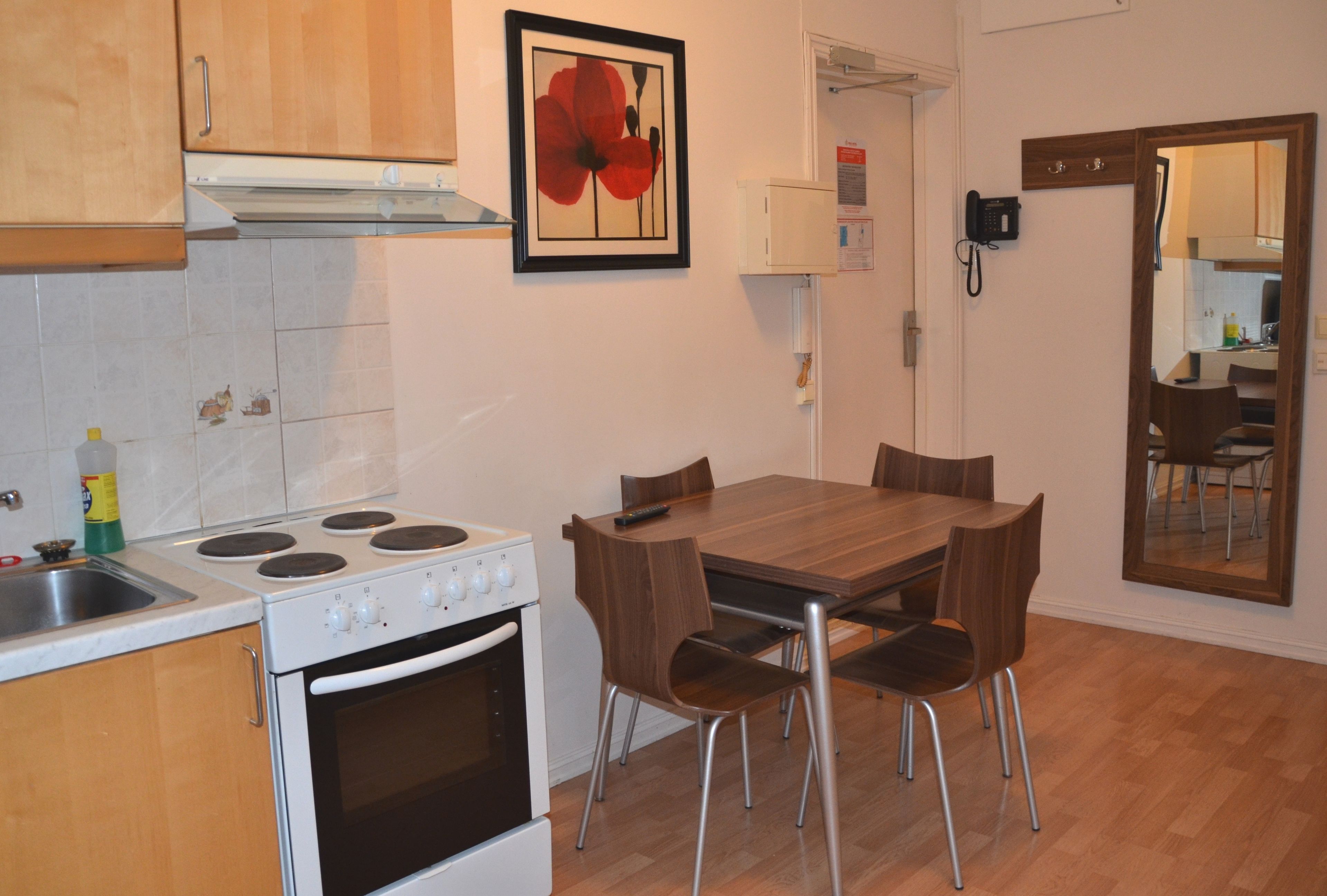 Una cocina compacta con estufa, horno y mesa de comedor con sillas.