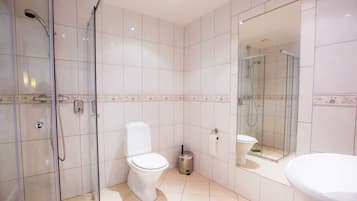 A modern bathroom with a glass-enclosed shower, a toilet, and a large mirror.