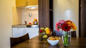 Una mesa de comedor con un tazón de fruta, un tazón de galletas y un jarrón con flores.