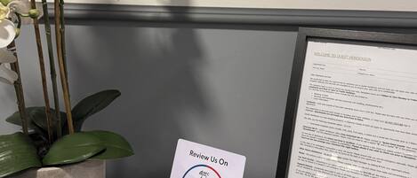 A reception desk with a framed welcome sign, a potted orchid, and a Google review card.