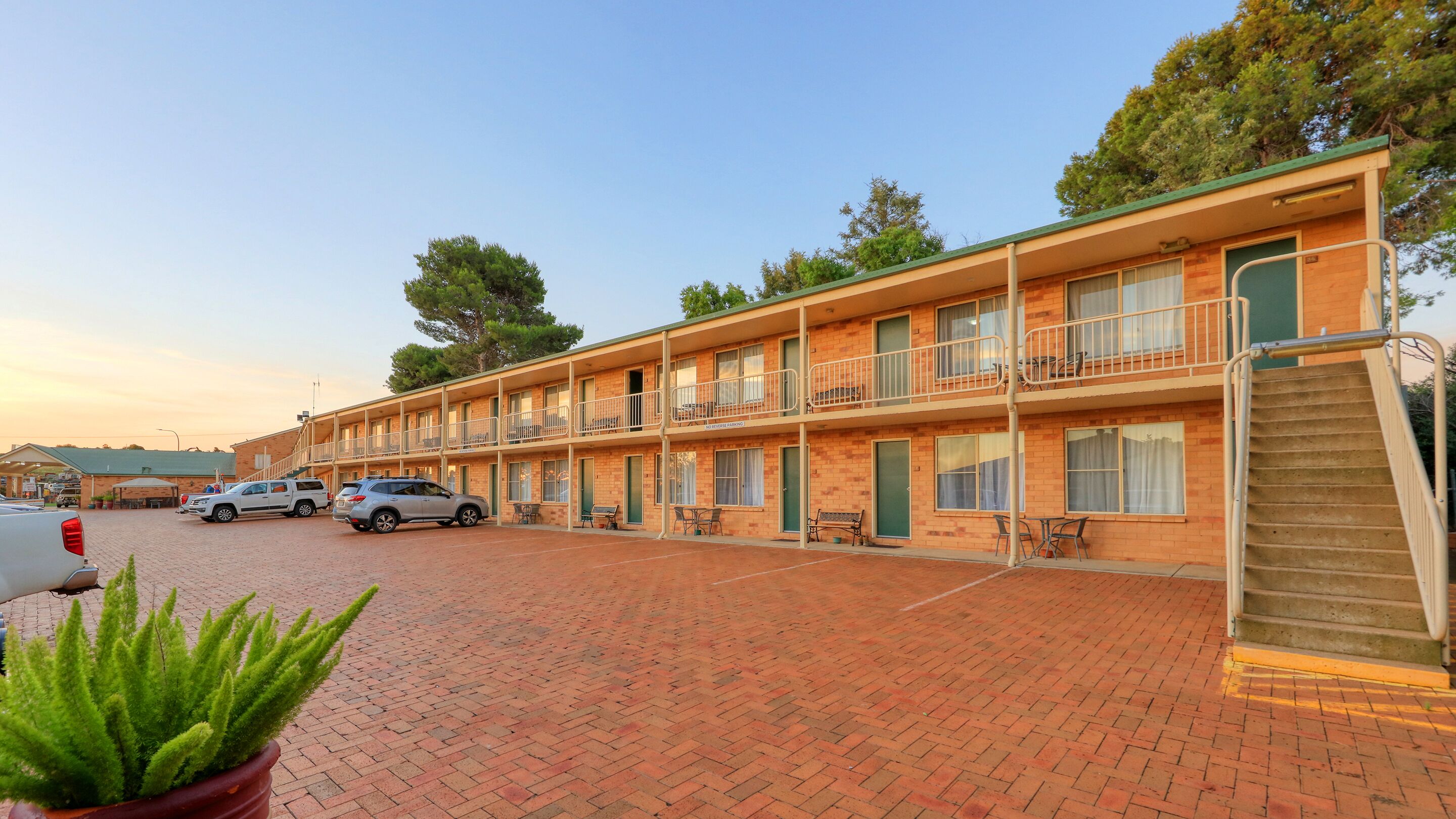 Un motel con fachada de ladrillo, varios balcones y un estacionamiento.