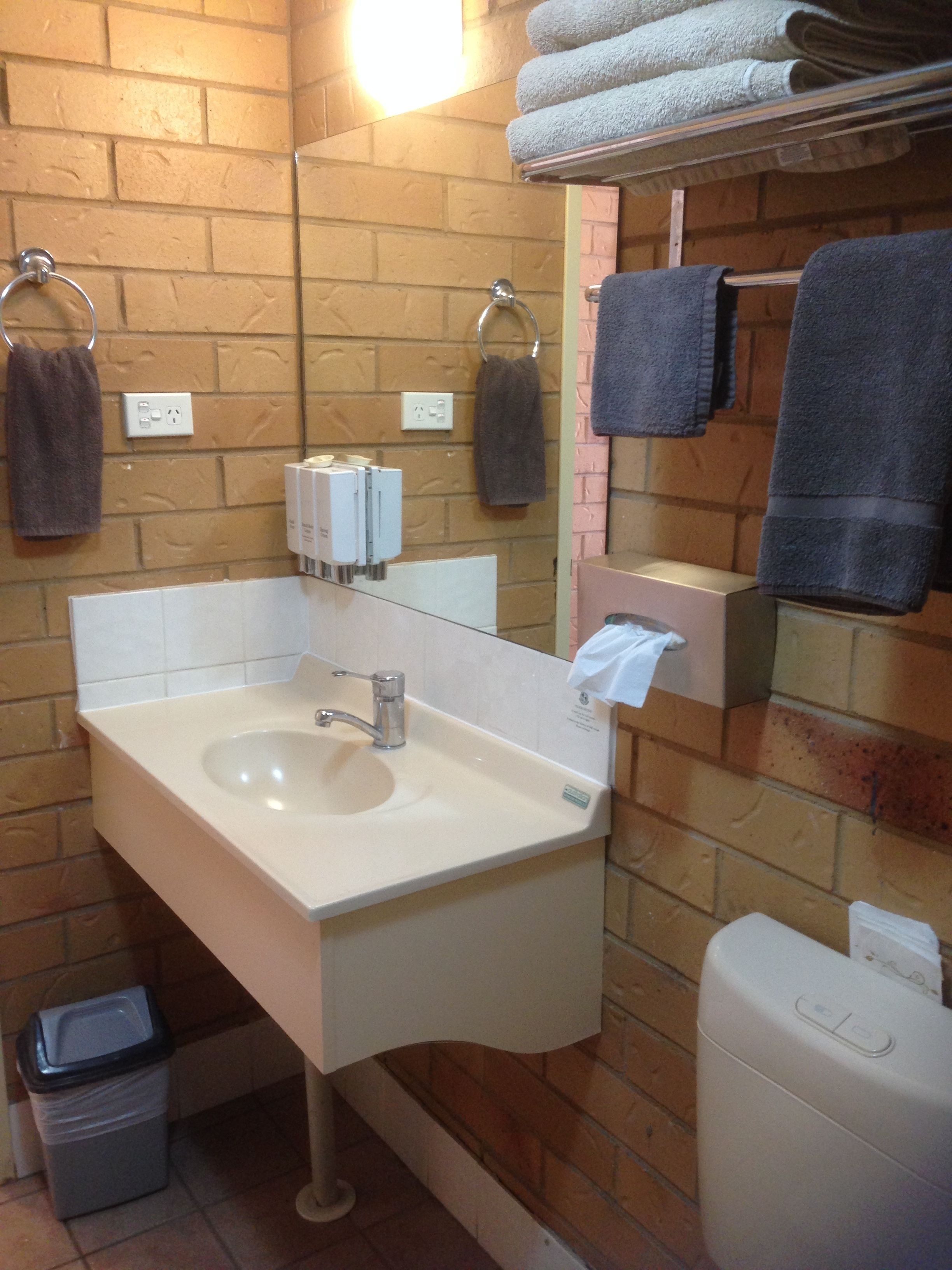 A bathroom with a sink, mirror, towel rack, and a trash bin.