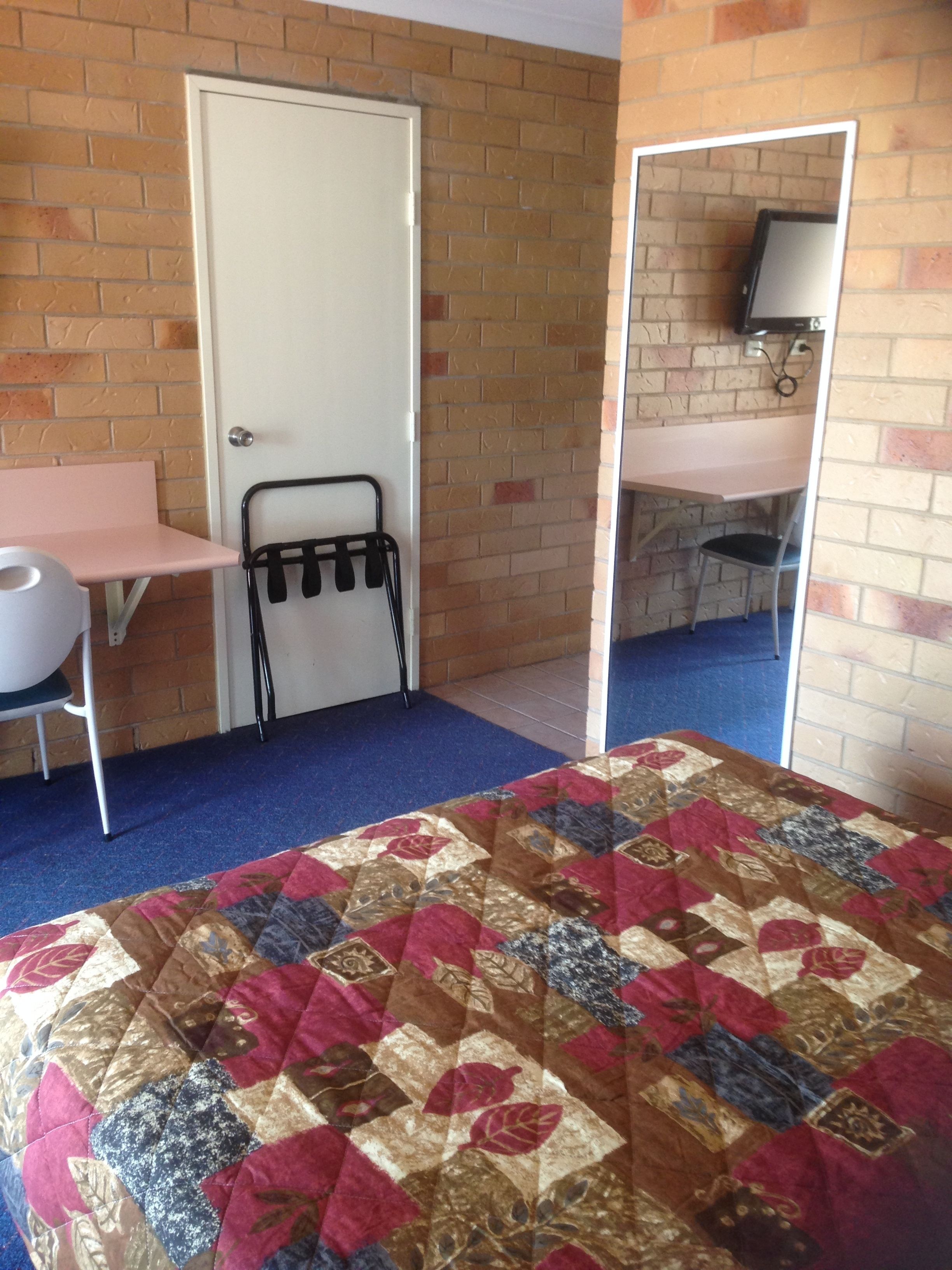 A room with a bed, a desk, a chair, and a door.