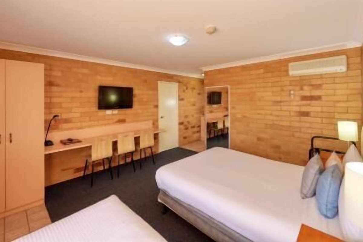 A hotel room with a bed, a desk, a TV, and a wardrobe.