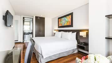 Una habitación de hotel moderna con una cama grande, mesita de noche, televisor y un cuadro en la pared.