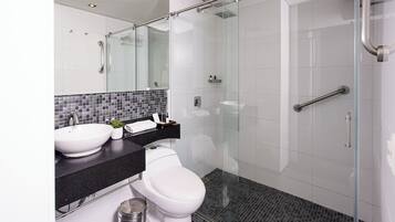 A modern bathroom with a glass-enclosed shower, a white toilet, and a black countertop with a sink and mirror.