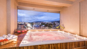 A spa room with a large window, a hot tub, towels, and a decorative lamp. - One Sixteen Hotel (Bogotá)