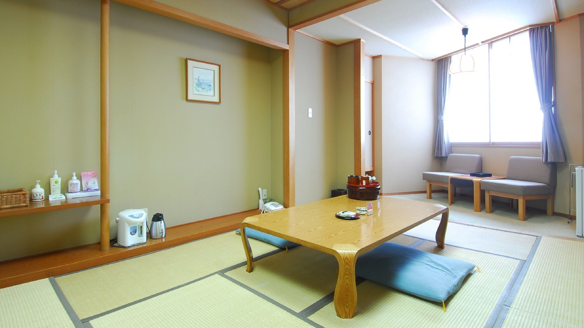 A traditional Japanese room with tatami flooring, a low wooden table, a cushioned bench, and a small shelf with toiletries.