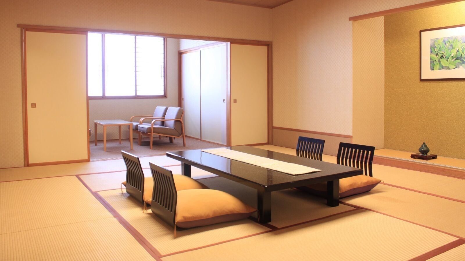 A tatami mat room with a low table and chairs, a sliding door, and a window.