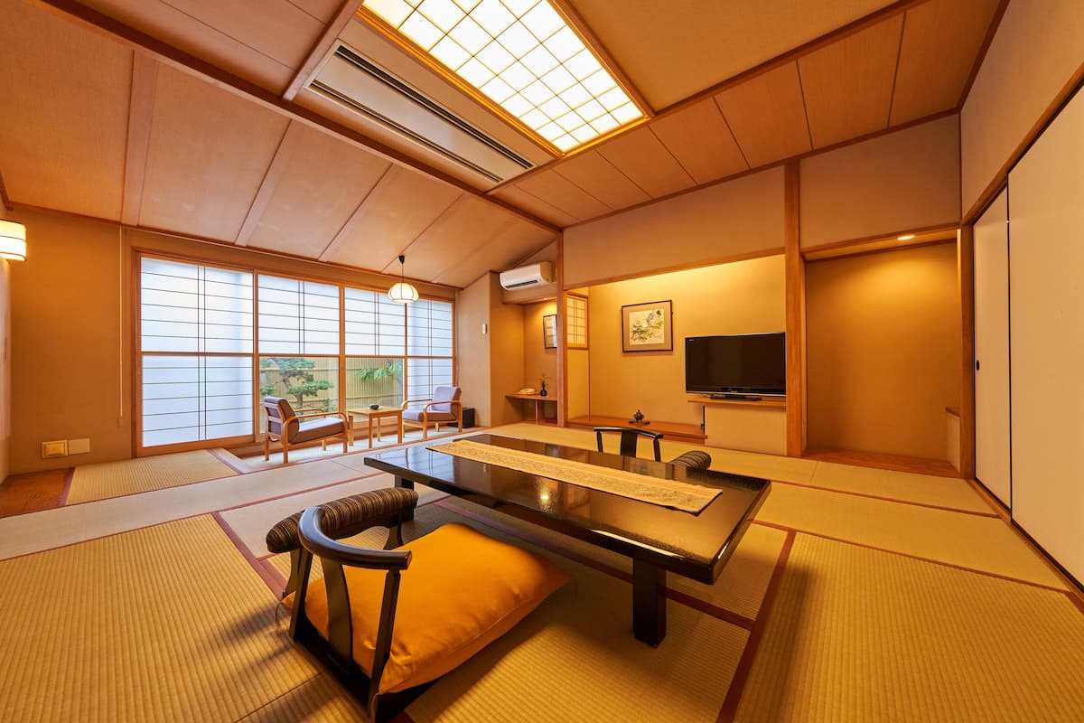 A traditional Japanese-style room with tatami flooring, a low table, and seating.