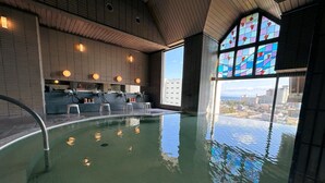 Una piscina interior con vistas a la ciudad a través de amplios ventanales.