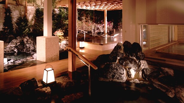 Un jardín interior tranquilo con un sendero de madera, detalles de piedra y un farol.