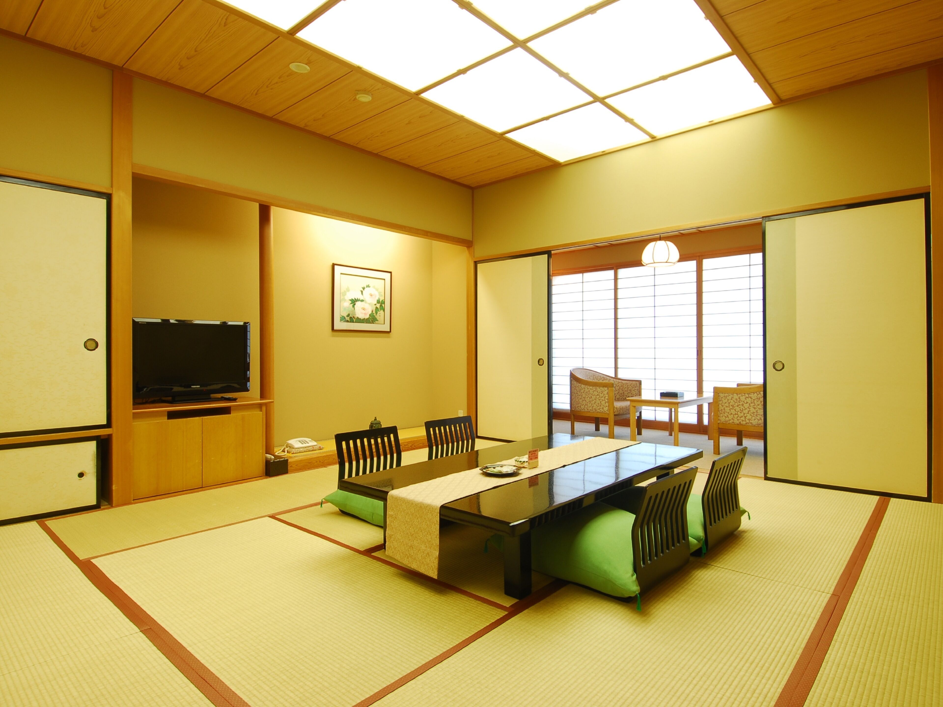Una habitación tradicional japonesa con suelo de tatami, una mesa baja y sillas.