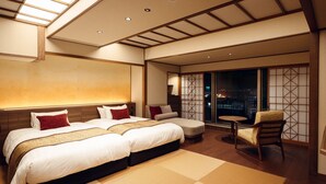 Habitación de hotel con una cama grande, zona de estar y vista nocturna de la ciudad.
