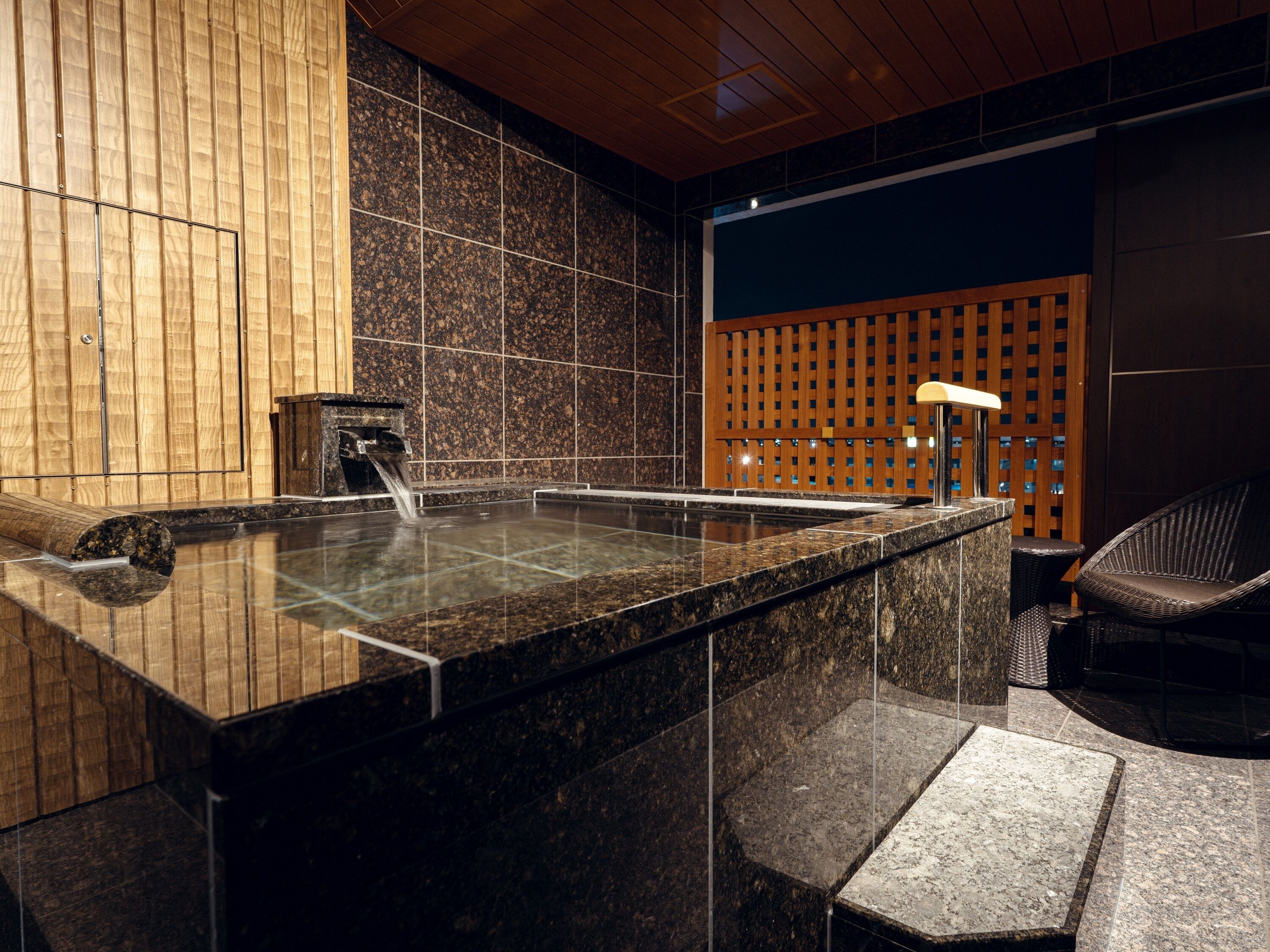 A spa area with a hot tub, wooden panel walls, and a seating area.