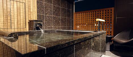 A spa area with a hot tub, wooden panel walls, and a seating area.