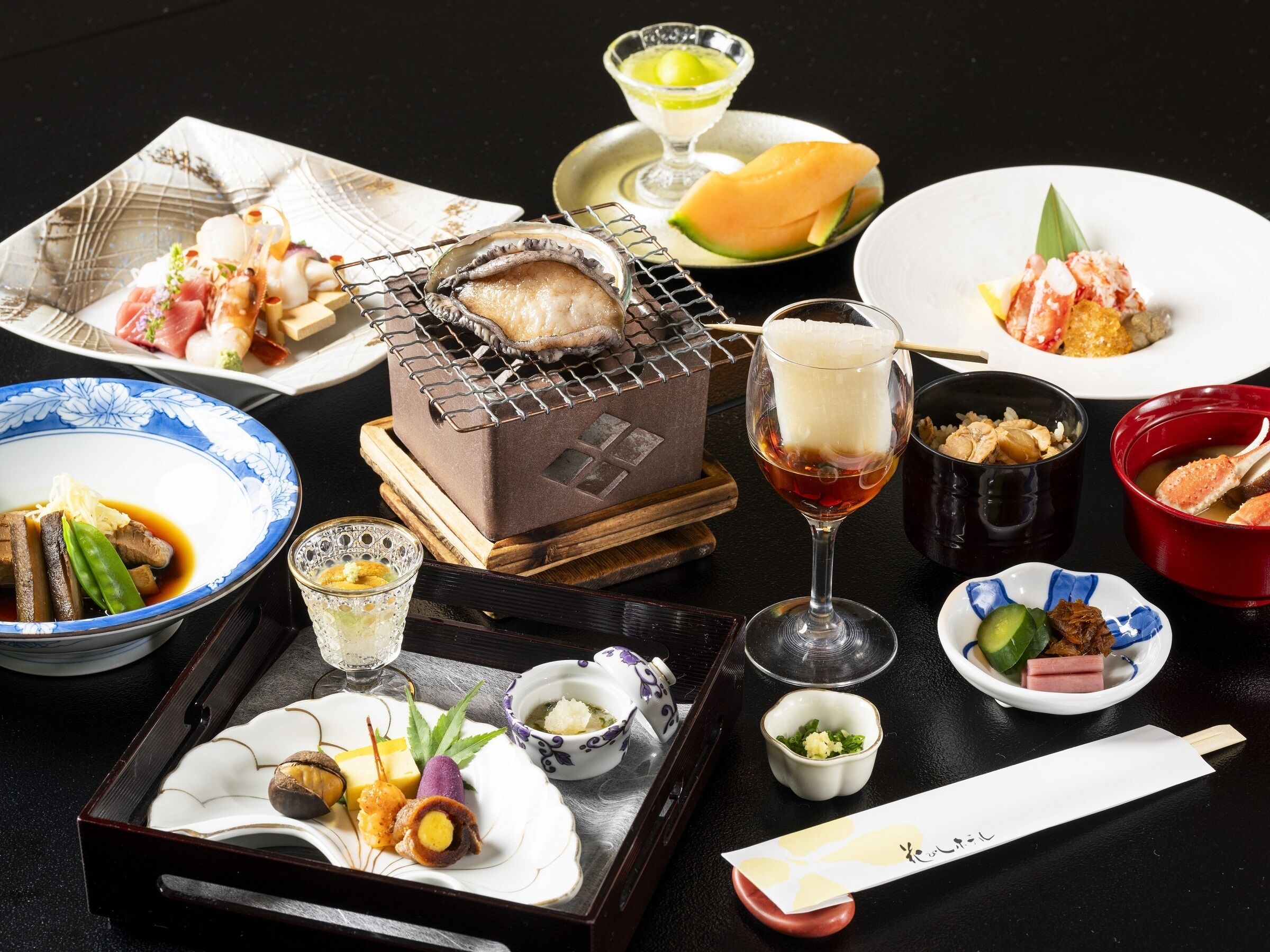 Forskellige japanske retter, herunder sushi, sashimi og en varm gryderet, anrettet på et bord.