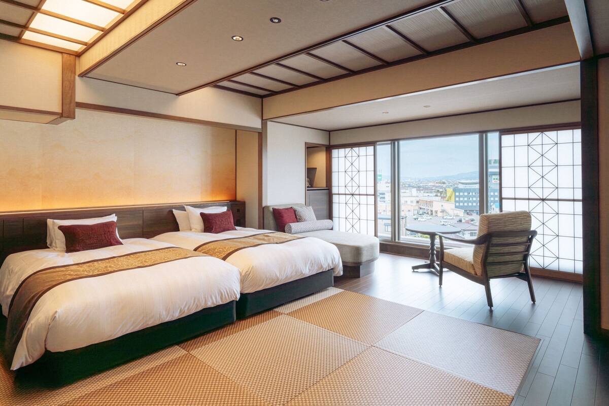 A modern hotel room with a large bed, a seating area, and a view of the city.