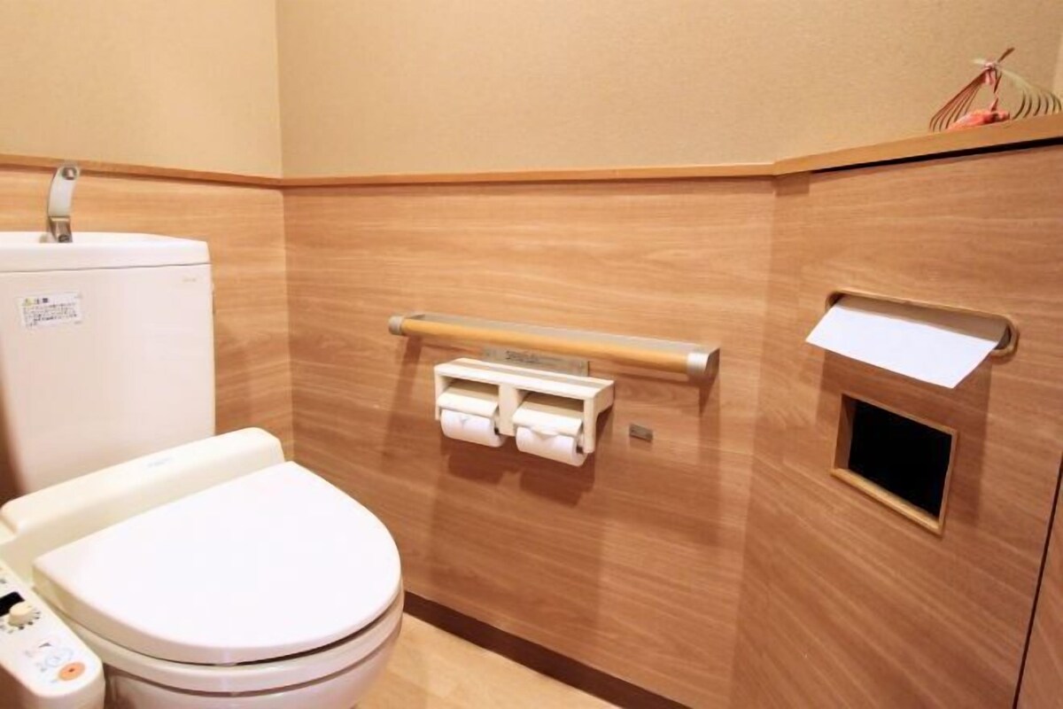A bathroom with a toilet, a hand dryer, and a paper towel dispenser.