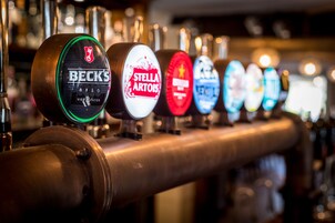 Una fila de grifos de cerveza con etiquetas que incluyen BECK'S, STELLA ARTOIS, entre otras.