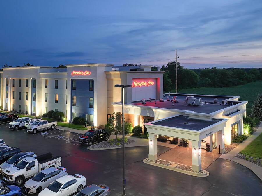 Un hotel Hampton Inn con estacionamiento, un área exterior techada y vistas del paisaje circundante.
