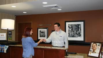 A reception desk with a framed welcome sign, a framed black and white photo, and a framed picture of a person.