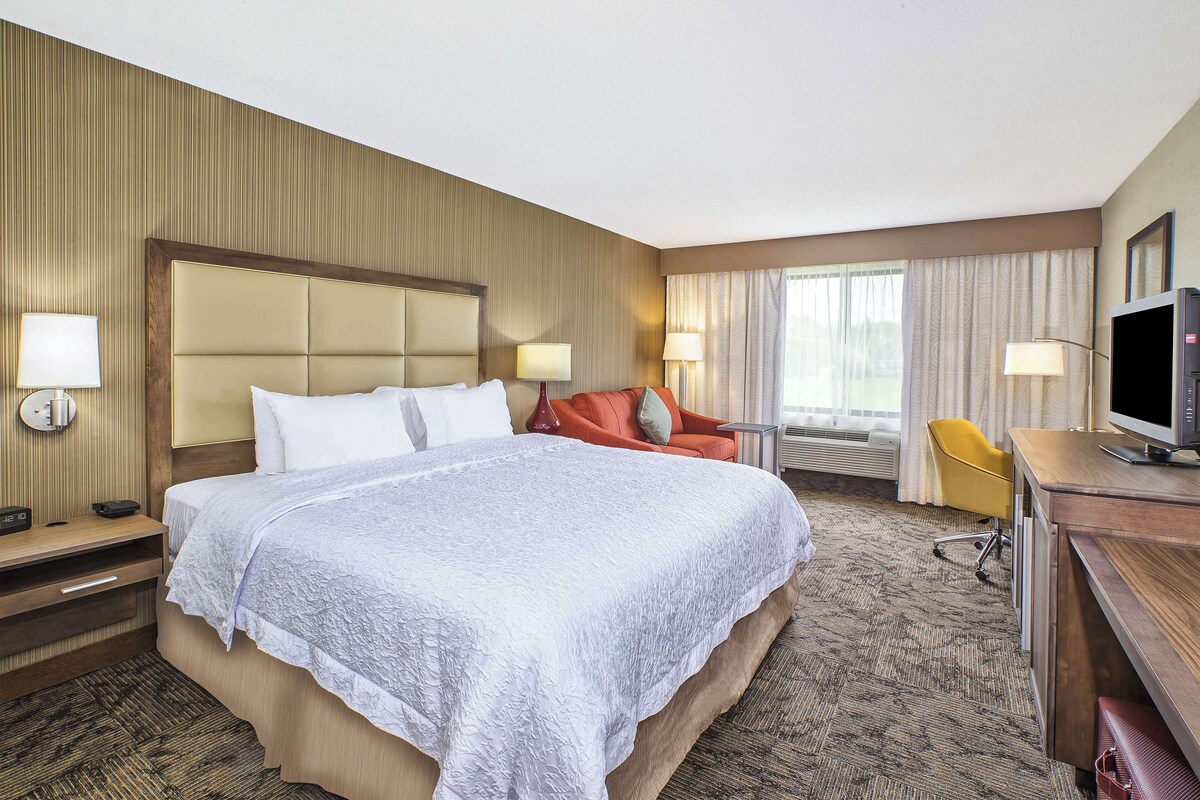 Een hotelkamer met een groot bed, een bureau met een televisie en een stoel.