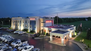 A Hampton Inn hotel with a parking lot, a covered outdoor area, and a view of the surrounding landscape.
