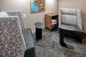 A room with patterned seating, a small wooden cabinet, and a painting on the wall. - Hampton Inn Tomah (Tomah)